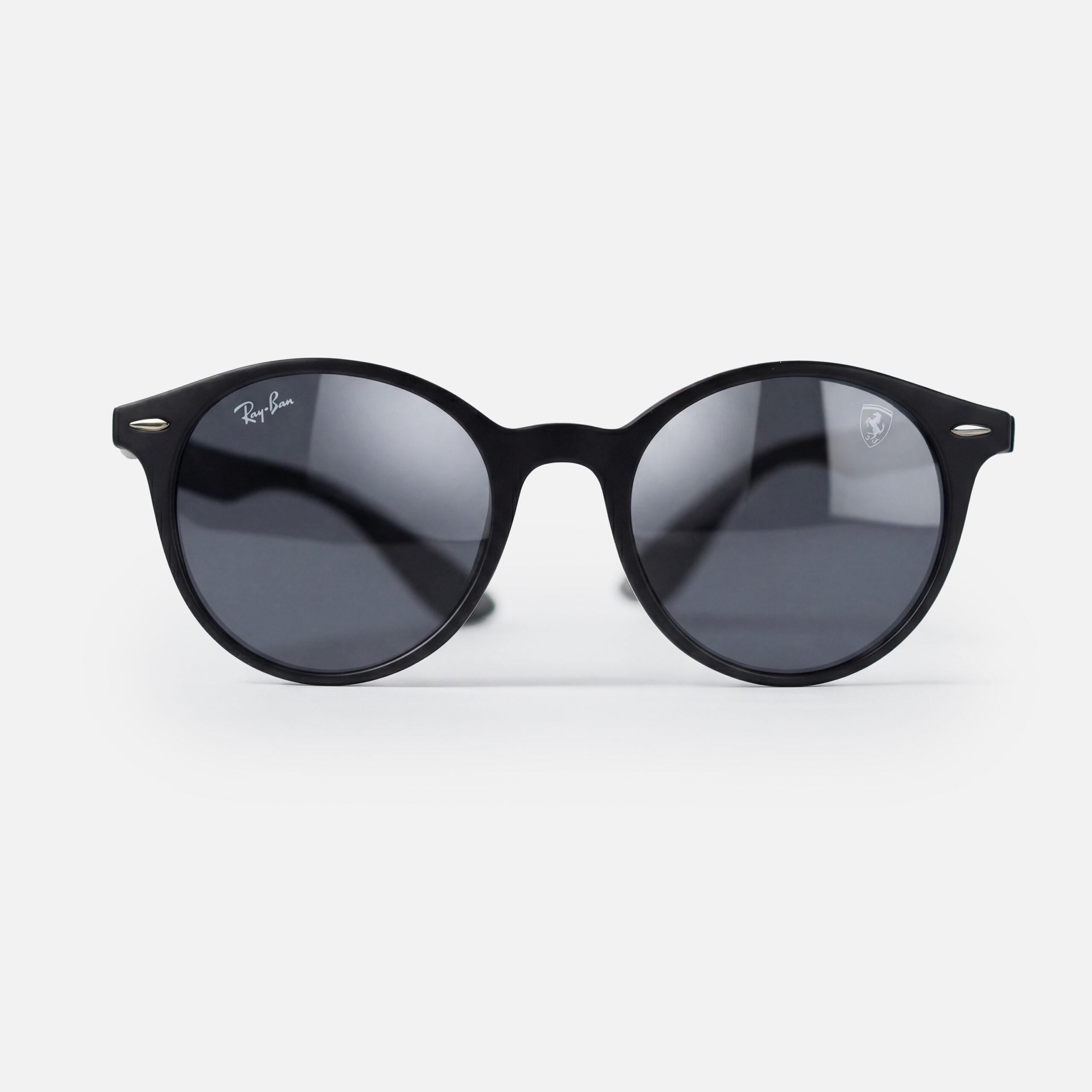 Matte black round sunglasses featuring dark grey lenses and a Scuderia Ferrari shield logo.