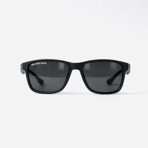 Matte black square sunglasses with dark lenses and a white Balenciaga logo on the lens.